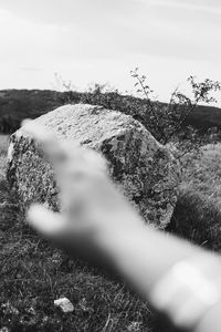 Close-up of hand on field against sky