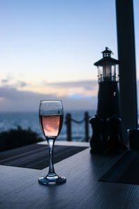 Close-up of wineglass on table against sky during sunset