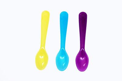 Directly above multi colored plastic spoons against white background