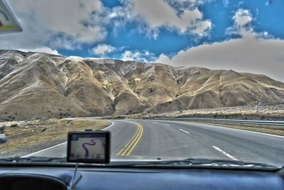 Road by mountains seen through car windshield