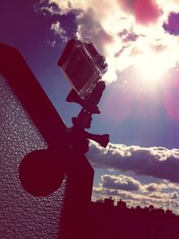 Low angle view of sun shining through clouds