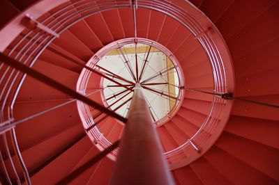 Low angle view of vibrant red spiral staircase in building