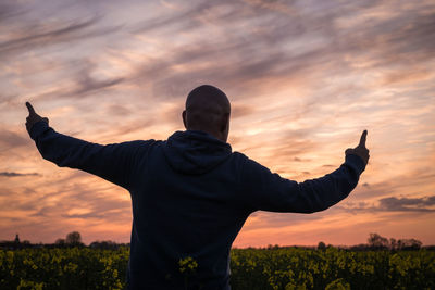 Silhouette man gesturing against cloudy sky during sunset