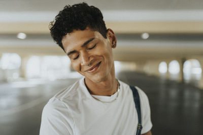 Smiling young man with eyes closed and pierced nose at parking garage