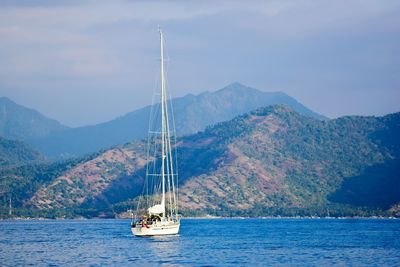 Sailboat sailing on sea against mountains