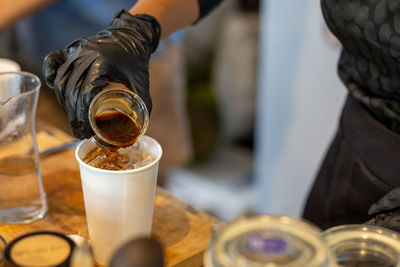 Close-up of hand pouring coffee in glass on table