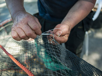 Midsection of man working with fishing net