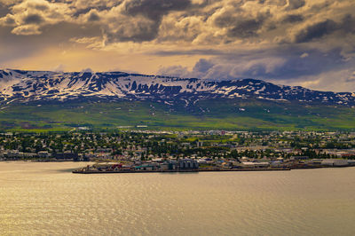 Aerial view of townscape by sea against sky