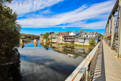 Buildings by river against sky in city