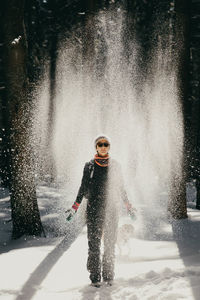 Full length of young woman playing with snow