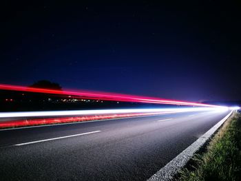 Light trails on road against sky at night