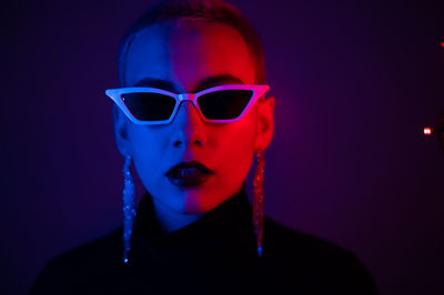 Portrait of woman wearing sunglasses against black background