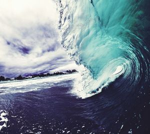 Scenic view of waves against cloudy sky