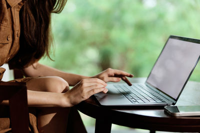 Midsection of woman using laptop at home