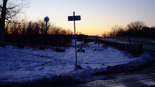 Snow covered field against sky during sunset