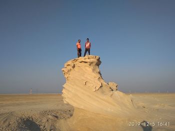 People on desert against clear sky