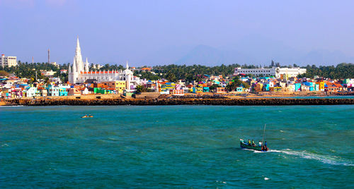 Boats in sea by city against sky