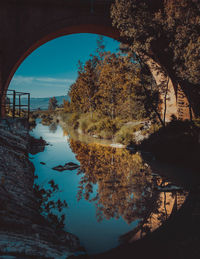 Arch bridge over river against sky during autumn