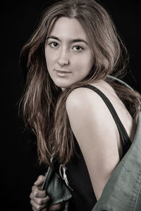 Portrait of smiling young woman against black background