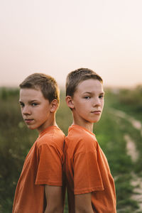 Funny twin brother boys playing outdoors on field at sunset.