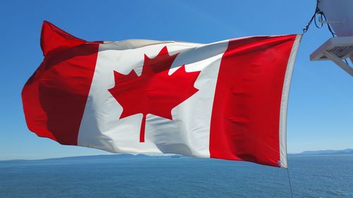 Canadian flag waving against sea