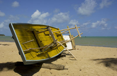 Deck chairs on beach against sky