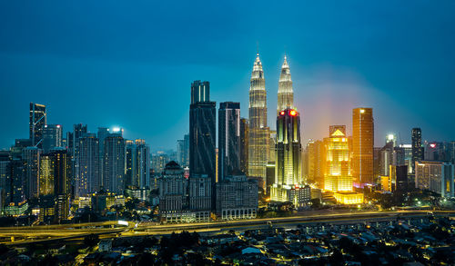 Illuminated buildings in city against sky