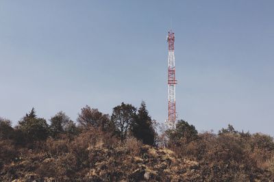 Communication tower amidst trees against clear sky