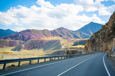 Empty road by mountains against sky