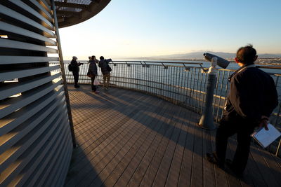 People looking at sea from observation point against sky