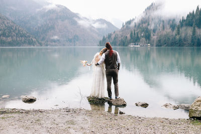 A happy couple in love and married embrace in nature by the lake and the misty mountains