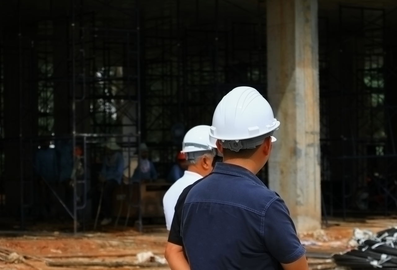 REAR VIEW OF MAN WORKING WITH CONSTRUCTION