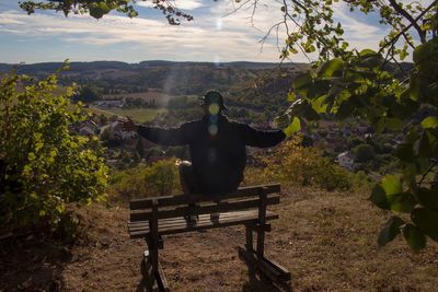 Man sitting on bench against trees