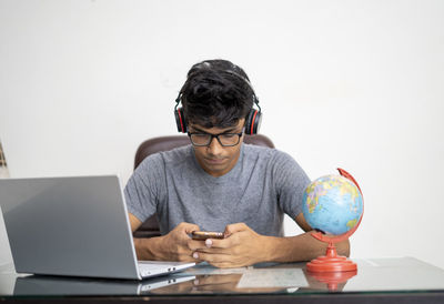 Man using mobile phone while sitting on table