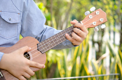 Cropped image of man playing guitar in yard