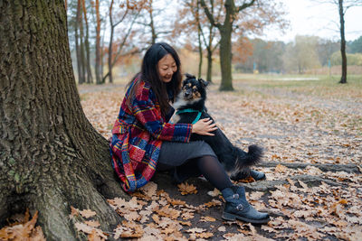 Portrait of young woman petting a dog near a big tree