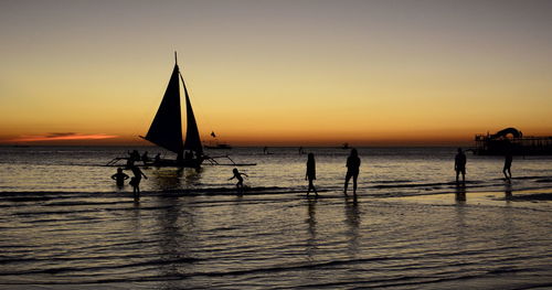Silhouette sailboat in sea against sky during sunset