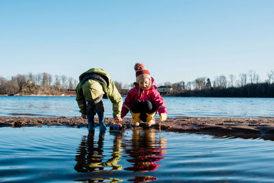 Siblings playing together at a sunny beach in winter in sweden