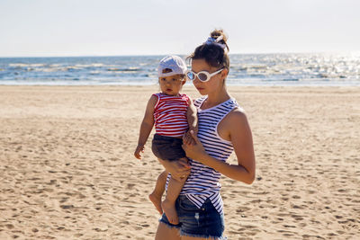 Woman walks with her little son on a sandy beach near the sea in the summer