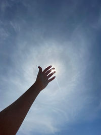 Low angle view of hand against blue sky