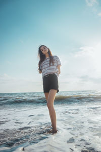 Full length of young woman standing on beach