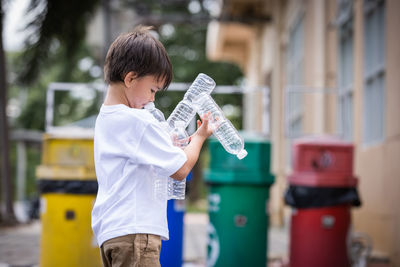 Full length of boy holding bottle while standing outdoors