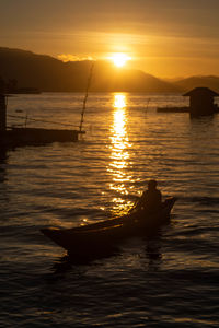 Silhouette boat in sea against sky during sunset