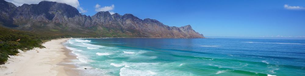 Scenic view of sea and mountains against blue sky