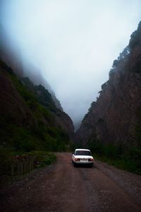 Cars on road by mountain against sky