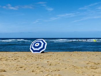 Deck chairs on beach against blue sky