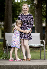 Full length portrait of smiling girl embracing mother outdoors