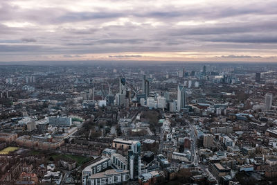 High angle view of city buildings against cloudy sky