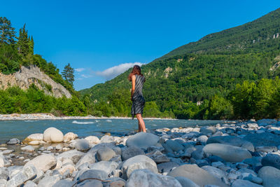 Full length of woman standing by river in forest