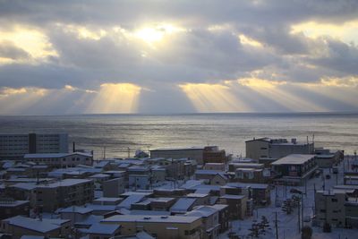 Buildings by sea against sky during sunset